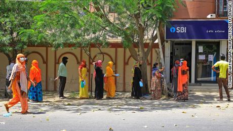 People wait outside a bank while locking on April 9 in Jaipur, Rajasthan, India.