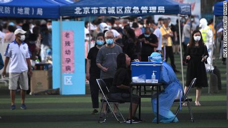 A healthcare worker wearing a protective suit takes a swab from a woman at a test center set up for people visiting or living in the Xinfadi market in Beijing.