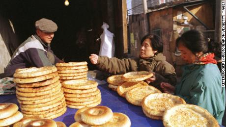 A Uyghur man sells traditional flat bread to women shopping along Beijing's Xinjiang Street in 1999.