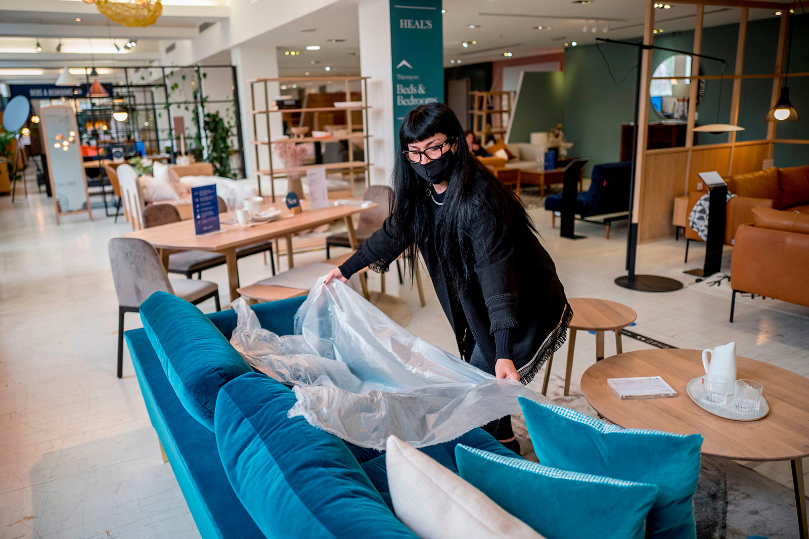 A woman demonstrates the use of plastic film for customers to test the sofas at Heal's flagship store, which reopened in central London on June 8.
