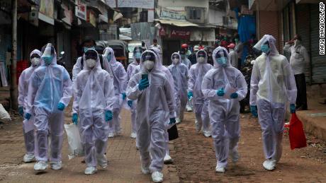 Health workers arrive at a health camp on June 28 in a slum area in Mumbai, India