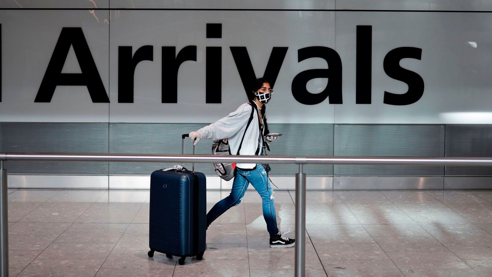 A passenger wearing a face mask as a precaution against the coronavirus arrives at Heathrow airport