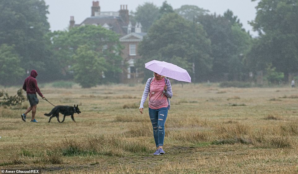 People walk through Wimbledon Common in the pouring rain as the country begins to see bursts of rain and cloud after days of sunshine