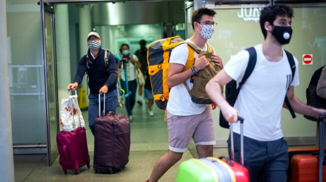 Travellers wearing face masks arrive from Paris to St Pancras Station in London after quarantine restrictions were imposed